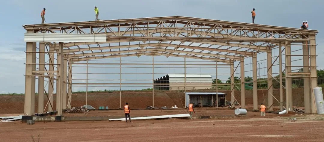 Carpentry Warehouse Nakasongola — steel portal frame erection with workers on roof